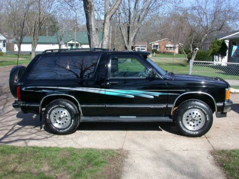 1995 Ford Crown Victoria - Black 1995 Chevrolet S-10 Blazer with teal graphics and aftermarket wheels is parked outside.
