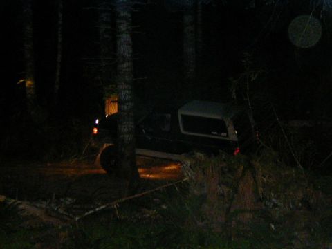 1994 Ford Explorer - A Ford Bronco is parked in a wooded area at night, illuminated by its headlights.