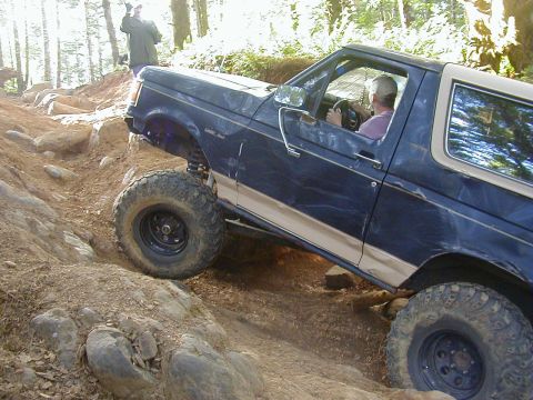 1994 Ford Explorer - Ford Bronco navigating a challenging off-road course with large rocks and steep inclines.