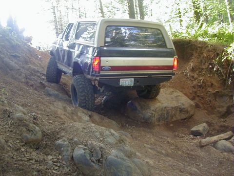 1994 Ford Explorer - A Ford Bronco navigates a challenging off-road trail with large rocks and steep inclines.