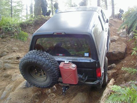 1994 Ford Explorer - This SUV is navigating a difficult off-road trail with large rocks and trees.