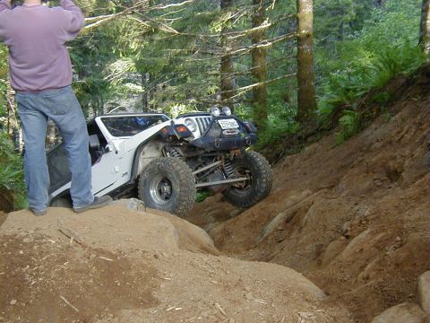 1994 Ford Explorer - Jeep Wrangler navigating a challenging off-road course in a wooded area.