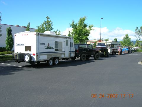 1996 Ford Bronco - A line of vehicles, including a black Ford Bronco and several RVs, are parked in a lot on a sunny day.
