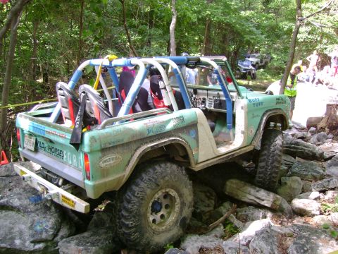 1969 Ford Bronco - This modified off-road vehicle is shown navigating a challenging rocky course with other vehicles in the background.