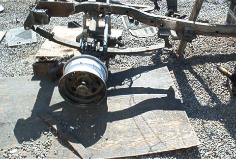 1982 Toyota 4Runner - Disassembled vehicle frame and a single wheel are laid out on plywood and gravel.
