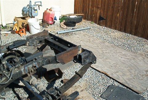 1982 Toyota 4Runner - Various vehicle frame and suspension parts are laid out on gravel and a piece of plywood.