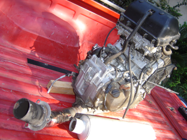 Inline-four motorcycle engine removed from bike with exhaust parts