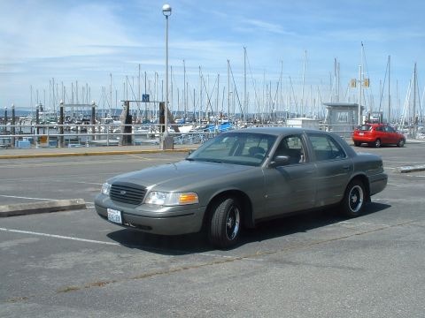 2000 Ford Crown Victoria - Gray 2000 Ford Crown Victoria parked near a marina with many sailboats.