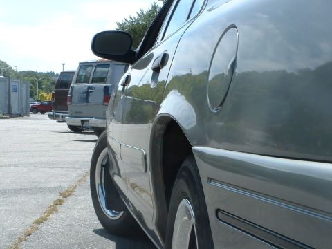 2000 Ford Crown Victoria - A car is parked in a lot with other vehicles and portable toilets visible.