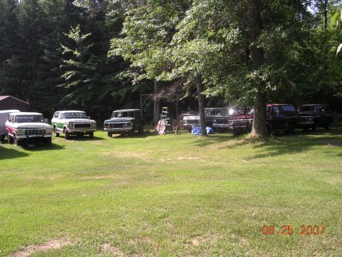 1978 Ford Bronco - A collection of Ford trucks and SUVs are parked in a yard, with one Bronco identified as a 1978 model.