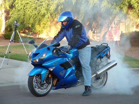 2007 Kawasaki Ninja - A rider on a blue motorcycle performs a burnout, creating a cloud of smoke.