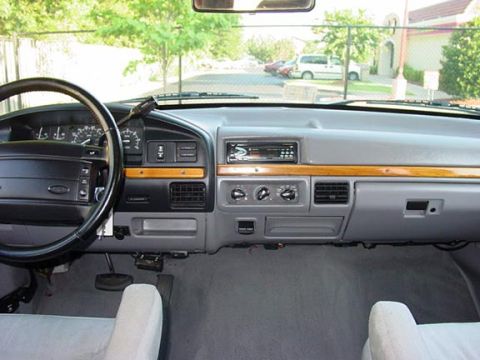 1994 Ford C-150 (Centurion Conversions) - The interior of a pickup truck is shown, with a view of the road and trees through the windshield.
