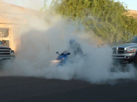 2007 Kawasaki Ninja - A blue motorcycle is engulfed in smoke, with two pickup trucks nearby.