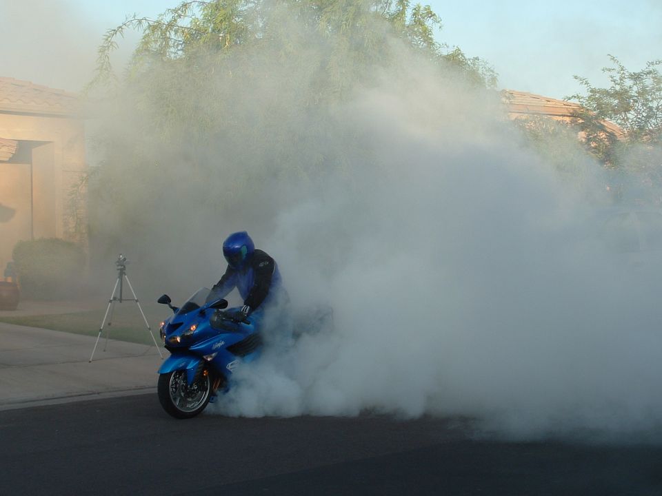 Blue 2007 Kawasaki Ninja doing a burnout in a cloud of smoke