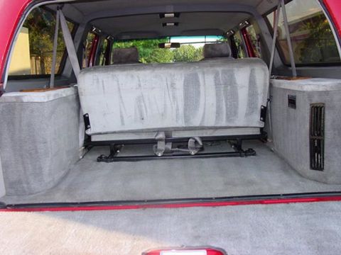 1994 Ford C-150 (Centurion Conversions) - Rear interior view of a red SUV, showing the cargo space and folded rear bench seat.
