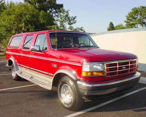 1994 Ford C-150 (Centurion Conversions) - This red SUV, likely a 1992 model, is shown from the front-three-quarter angle with a camper shell.