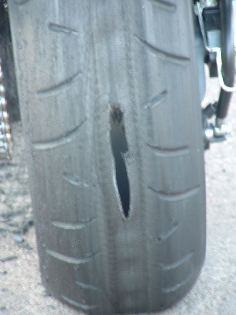 2007 Kawasaki Ninja - A motorcycle's rear tire is shown with a significant gash, indicating damage.