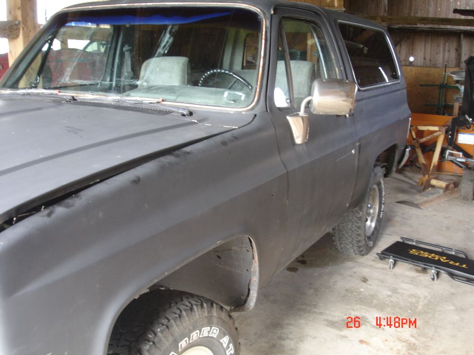 This is a 1985 Chevrolet K5 Blazer, seen from the front quarter angle. It's in a garage with some equipment in the background