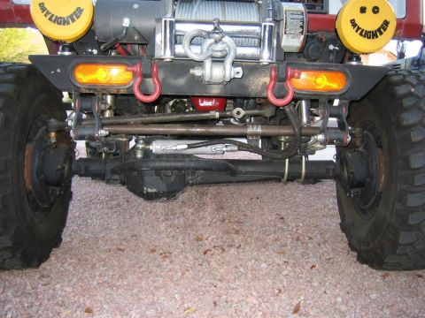 1987 Suzuki Samurai - Front view of a vehicle's bumper, a winch, tow hooks, and two yellow "Daylighter" lights.