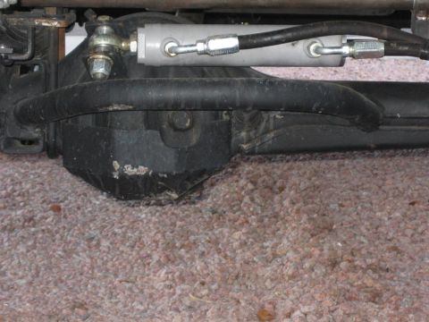 1987 Suzuki Samurai - Close-up of power steering cylinder and linkage on a vehicle's front axle.
