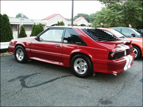 2001 Mercury Grand Marquis - A red coupe with louvers and racing stripes is parked next to another vehicle.