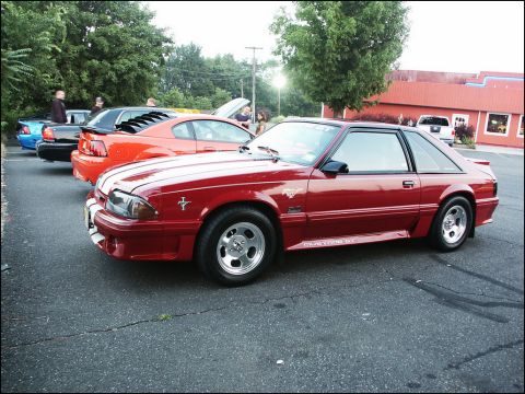 2001 Mercury Grand Marquis - A red 1987 Ford Mustang GT is parked in a lot with other vehicles.