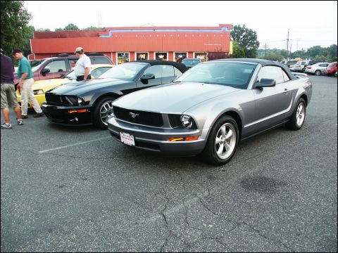 2001 Mercury Grand Marquis - Two Ford Mustang convertibles are parked in a lot outside a building.