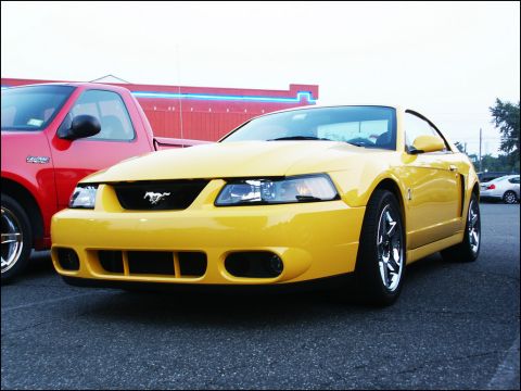 2001 Mercury Grand Marquis - Front view of a yellow Ford Mustang with a red pickup truck beside it.