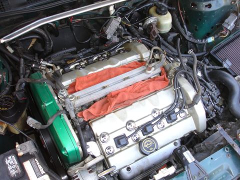 1993 Ford Taurus - Engine bay with various components and wiring, including a green valve cover and silver intake manifold.