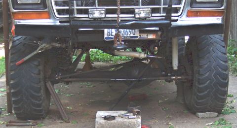 1978 Ford Bronco - The front suspension and large tires of a lifted vehicle are visible, suggesting maintenance or modification work.