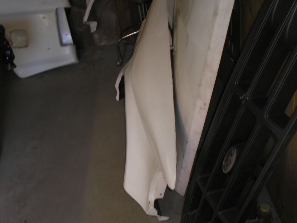 White car fender leaning against a black grille. Supermotors.net logo visible
