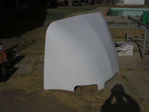 1999 Ford F-800 - A white truck hood is shown from the side, resting on the ground outdoors.