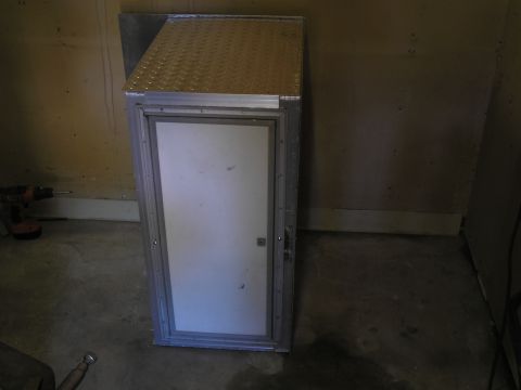 1999 Ford F-800 - This is an aluminum storage cabinet with a diamond plate top and a white door.