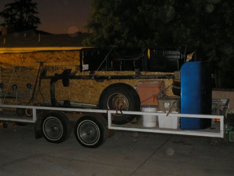 1989 Ford F-250 - A trailer carries various items including wood paneling, a metal frame, and a blue barrel.