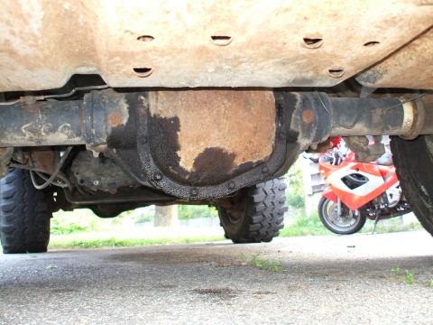 1994 Ford Bronco - The underside of a vehicle is shown, with a motorcycle partially visible in the background.
