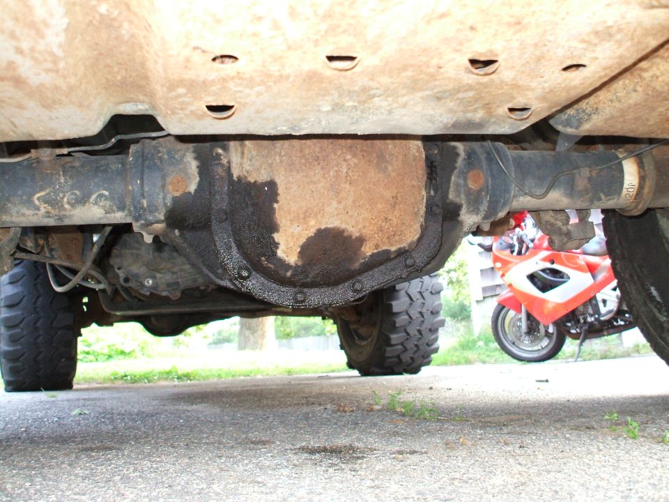 Rusty rear axle and grease-covered differential cover under a lifted 4x4 truck