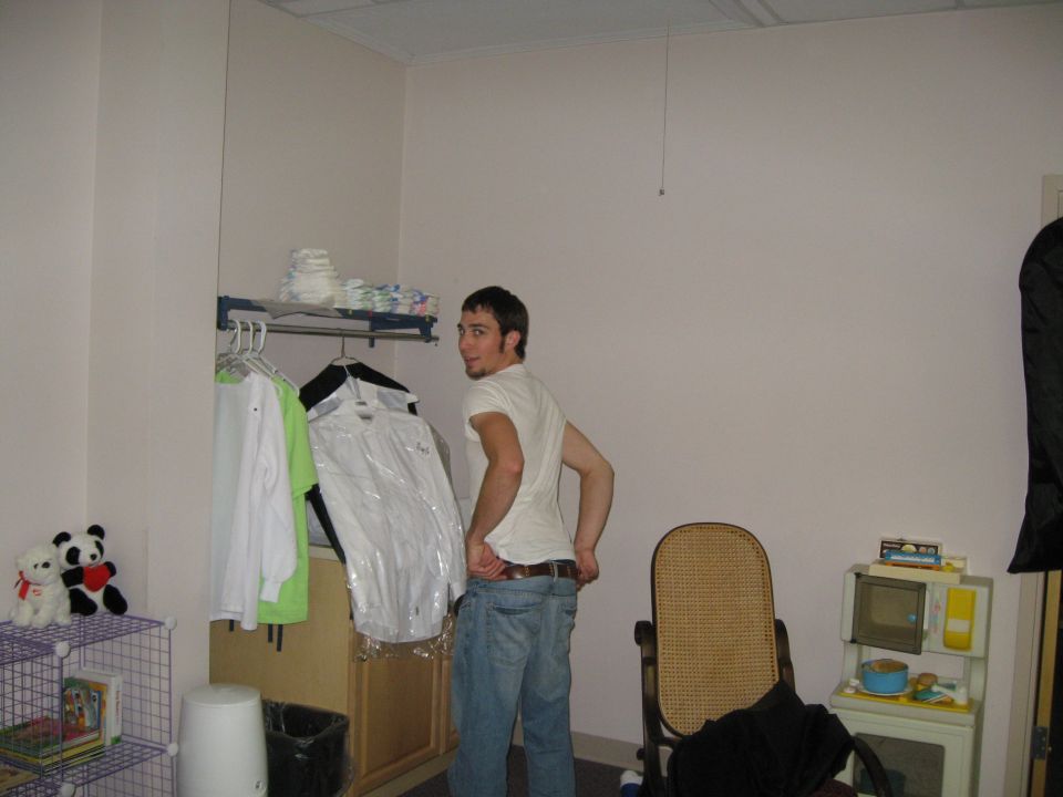 Man in a room with clothes on a rack and a toy microwave