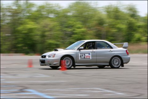 2001 Mercury Grand Marquis - A silver Subaru WRX STI navigates a race course, indicated by the cones and racing numbers on its doors.
