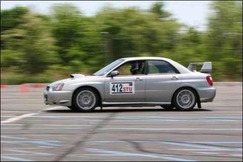 2001 Mercury Grand Marquis - Silver Subaru WRX STI sedan competes on a race track, indicated by racing cones and track markings.