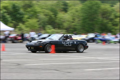 2001 Mercury Grand Marquis - Mazda Miata convertible with racing numbers participates in an event on a paved track with cones.