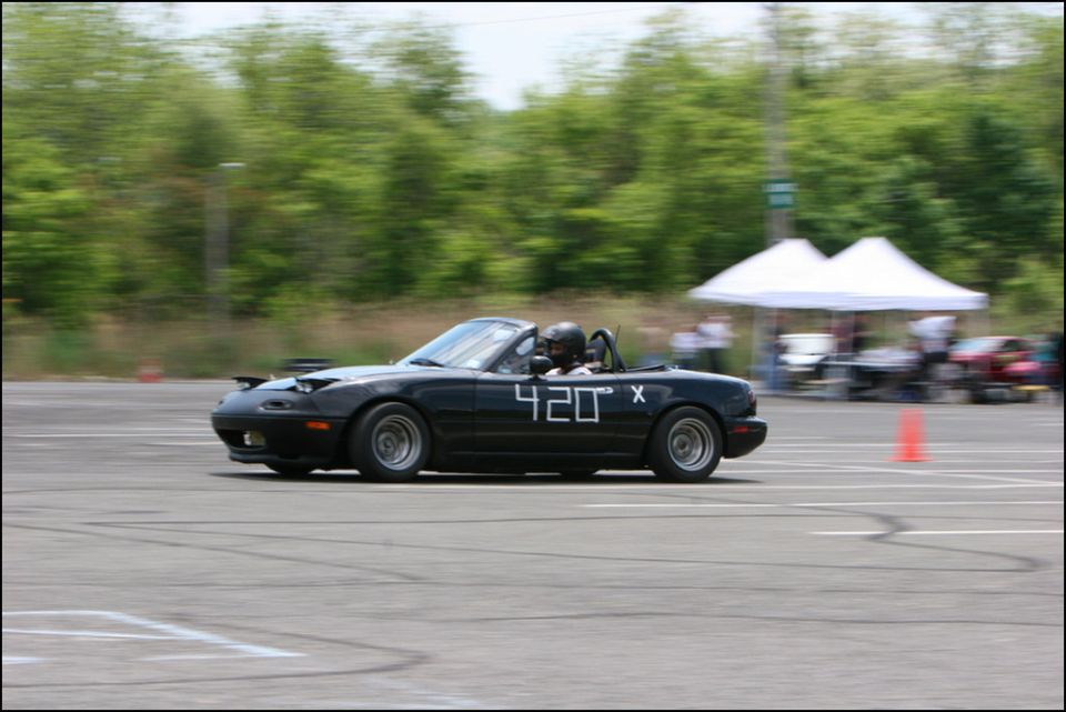 Black convertible sports car with racing numbers 420 X on the side, seen from the side at an autocross event