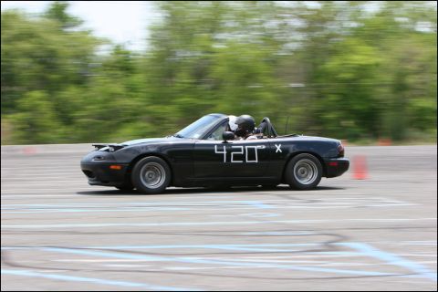 2001 Mercury Grand Marquis - Black convertible sports car with racing numbers on the door navigates a race track.