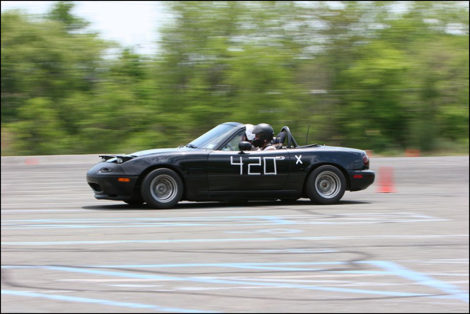 Black convertible sports car with racing numbers 420 and X on the door, on a race track