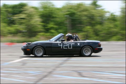 2001 Mercury Grand Marquis - A black convertible sports car with racing numbers drives on a track during an event.