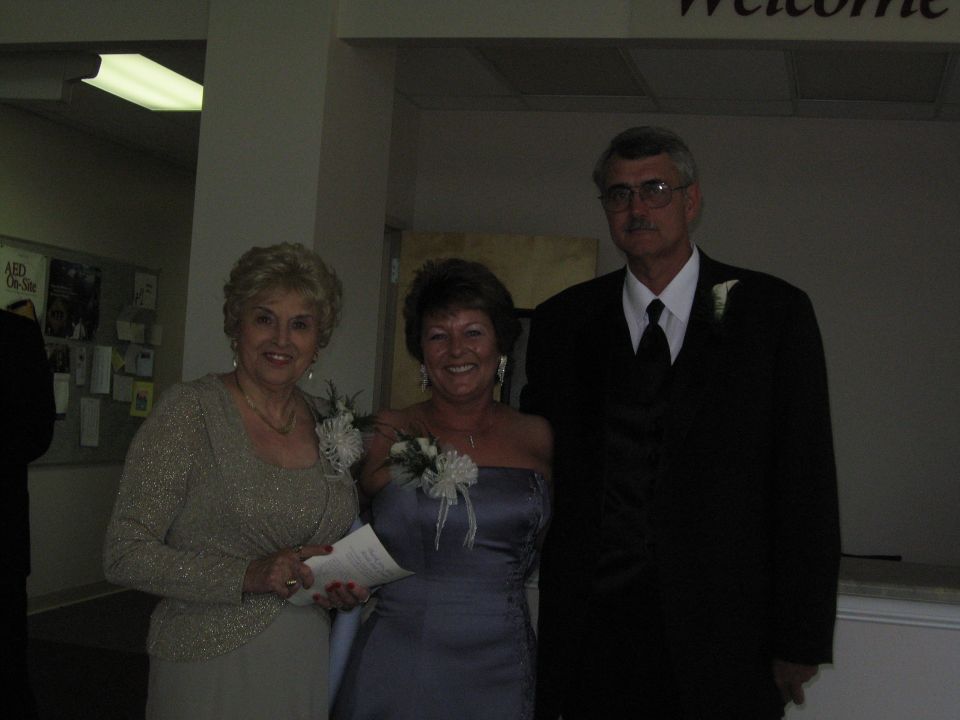 three people dressed up for an event, two women and a man