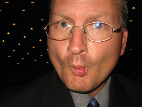 1988 Ford Bronco - A man in a suit and glasses puckers his lips for a photo in front of a dark, dotted background.