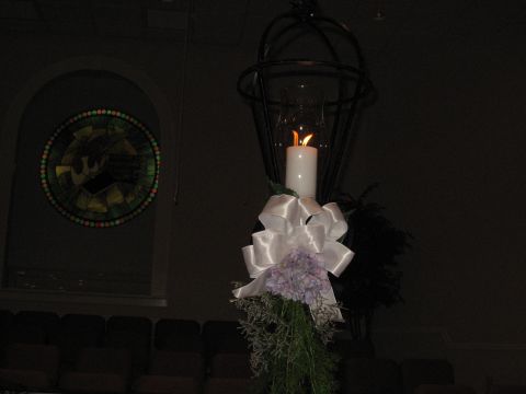 1988 Ford Bronco - A decorative candle with a white bow and flowers is lit, set against a dark background with a stained glass window.
