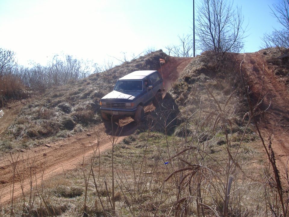 Dark SUV driving down a dirt hill, front grille visible