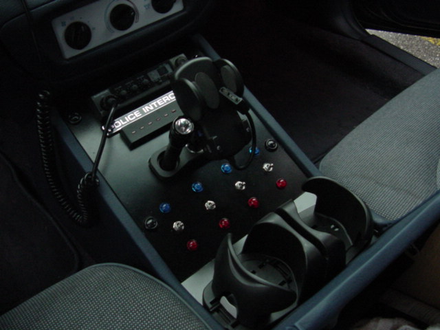 Center console with Police Interceptor radio, shifter, rows of colored toggle switches, cupholders