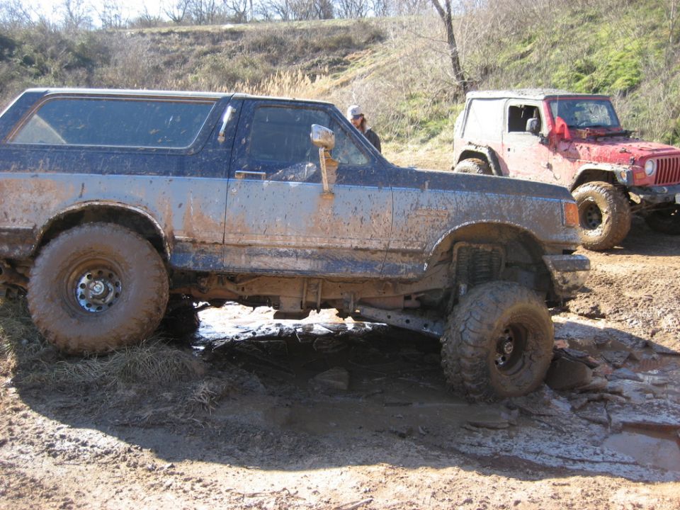 Mud-covered SUV and Jeep on rocky terrain